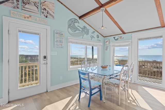 dining space with lofted ceiling with beams, a water view, and plenty of natural light