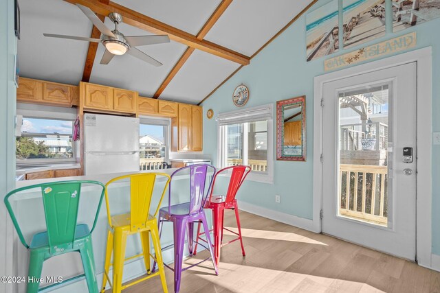 kitchen featuring ceiling fan, light brown cabinets, light hardwood / wood-style flooring, vaulted ceiling with beams, and white fridge