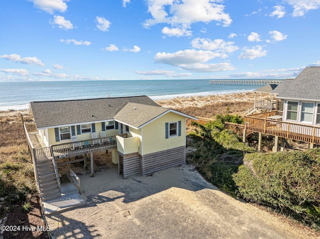 view of front of property featuring a deck with water view and a beach view