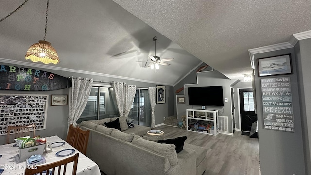 living room featuring ceiling fan, wood-type flooring, a textured ceiling, lofted ceiling, and ornamental molding