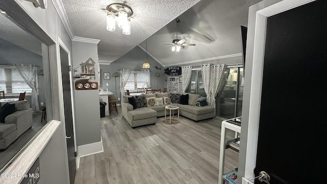 living room with hardwood / wood-style floors, vaulted ceiling, ceiling fan, ornamental molding, and a textured ceiling