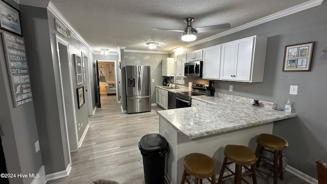 kitchen with white cabinets, a kitchen breakfast bar, kitchen peninsula, and stainless steel appliances