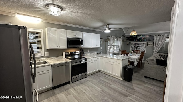 kitchen with white cabinets, ceiling fan, ornamental molding, kitchen peninsula, and stainless steel appliances