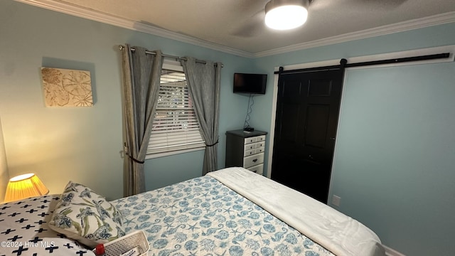 bedroom featuring ceiling fan, a barn door, and crown molding