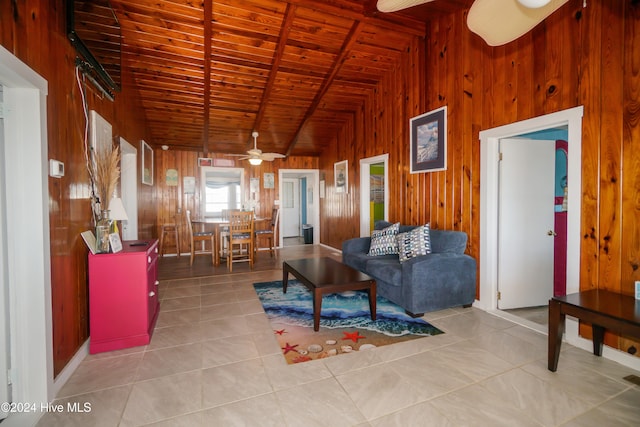 tiled living room featuring lofted ceiling with beams, ceiling fan, wood ceiling, and wooden walls