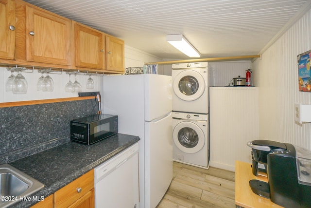 washroom featuring light wood-type flooring, stacked washing maching and dryer, crown molding, and sink