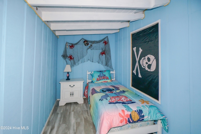 bedroom with beam ceiling and hardwood / wood-style flooring