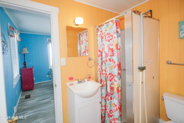 bathroom featuring vanity, wood walls, crown molding, toilet, and wood-type flooring