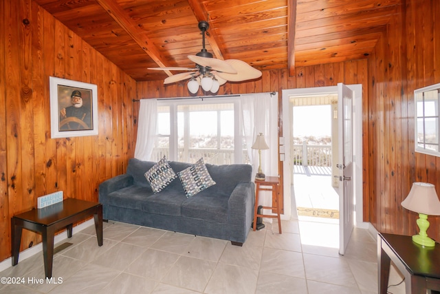 tiled living room featuring vaulted ceiling with beams, wood walls, ceiling fan, and wood ceiling