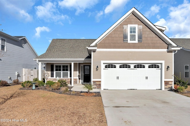 craftsman-style home with covered porch, a garage, and a front lawn