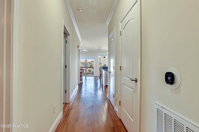 hall with light hardwood / wood-style flooring and ornamental molding