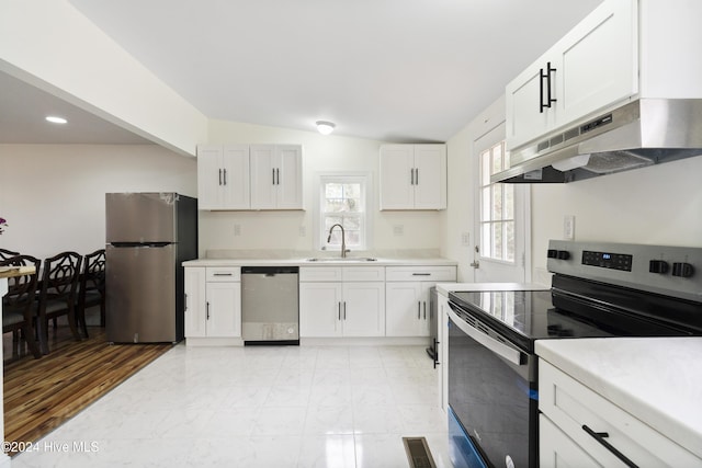 kitchen with stainless steel appliances, white cabinetry, lofted ceiling, and sink