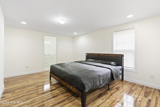 bedroom featuring connected bathroom and light hardwood / wood-style flooring