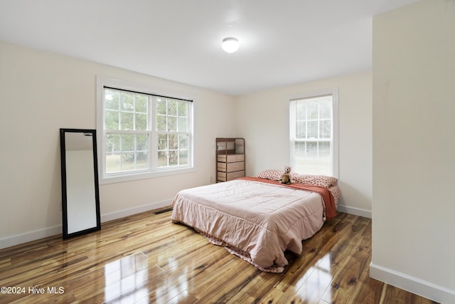 bedroom with hardwood / wood-style flooring and multiple windows