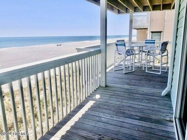 wooden terrace featuring a water view and a view of the beach