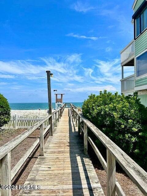 view of dock with a water view and a beach view