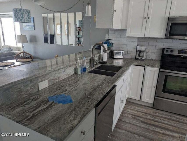 kitchen with dark hardwood / wood-style flooring, stainless steel appliances, sink, decorative light fixtures, and white cabinetry