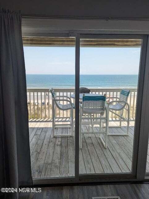 interior space featuring a beach view, a water view, dark hardwood / wood-style floors, and a healthy amount of sunlight