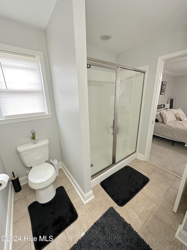 bathroom with crown molding, tile patterned flooring, a shower with door, and toilet