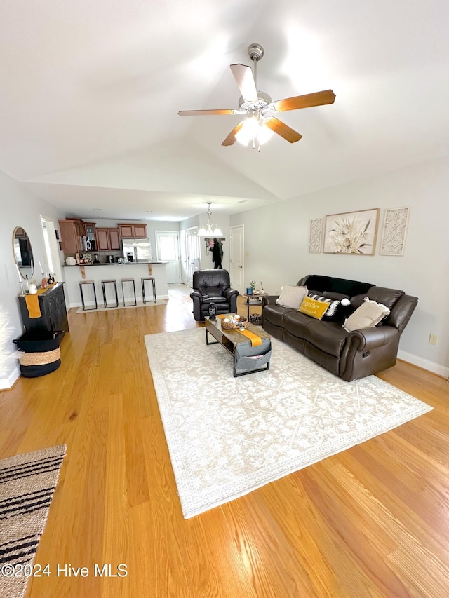 living room featuring lofted ceiling, wood-type flooring, and ceiling fan with notable chandelier