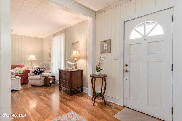 foyer entrance with hardwood / wood-style floors, crown molding, and wooden walls