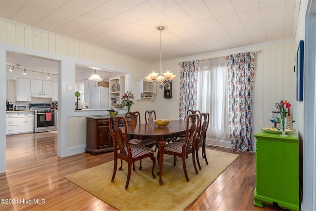 dining area with wood-type flooring and a notable chandelier