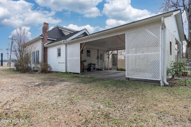 view of side of property featuring a lawn and a carport