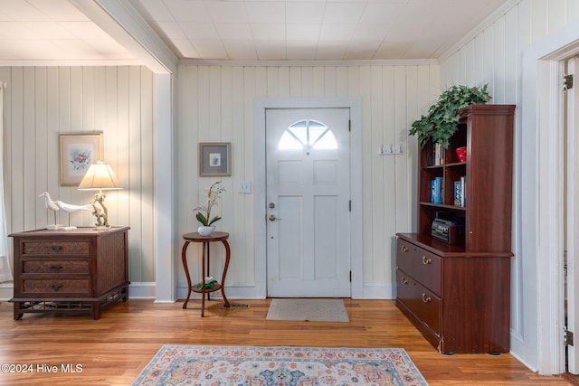 entryway featuring wooden walls, light hardwood / wood-style floors, and crown molding