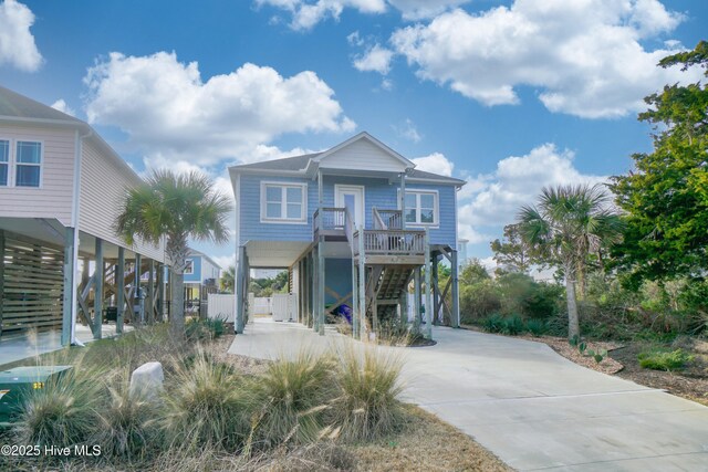 coastal inspired home featuring stairway, a porch, driveway, and a carport