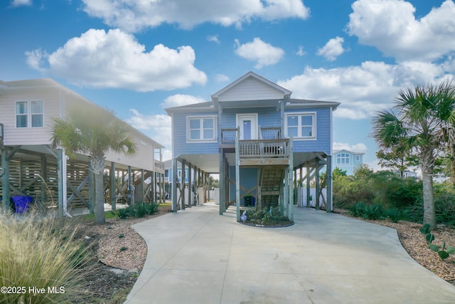 coastal inspired home featuring a carport, a porch, driveway, and stairway