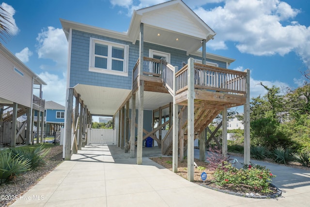 coastal inspired home with a carport, fence, a gate, and a deck