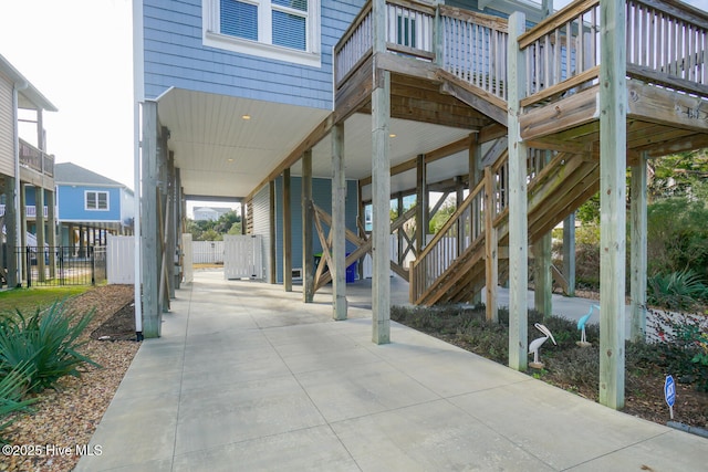 view of patio featuring fence, a deck, and stairs