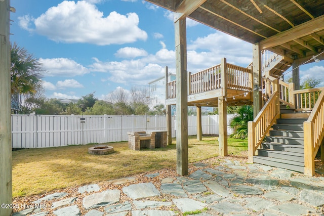 view of yard featuring a fenced backyard, a wooden deck, stairs, and an outdoor fire pit