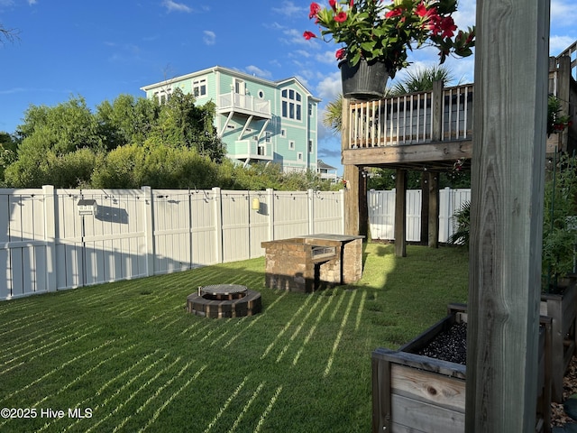 view of yard with a wooden deck, fence, and an outdoor fire pit