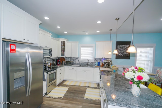 kitchen featuring white cabinetry, hanging light fixtures, stainless steel appliances, and sink