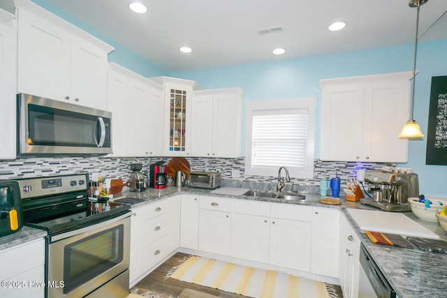 kitchen featuring pendant lighting, white cabinetry, sink, and appliances with stainless steel finishes