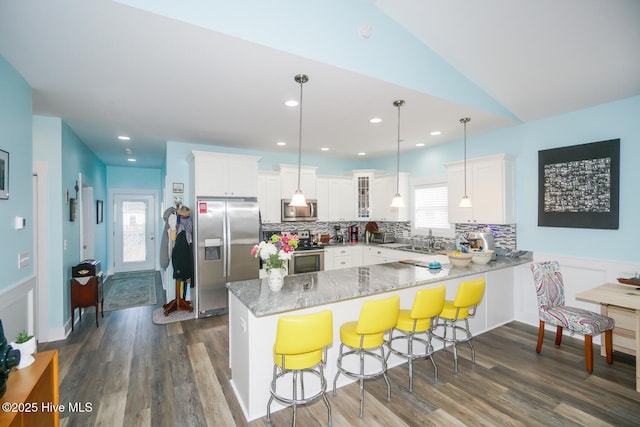 kitchen featuring kitchen peninsula, white cabinetry, stainless steel appliances, and decorative light fixtures