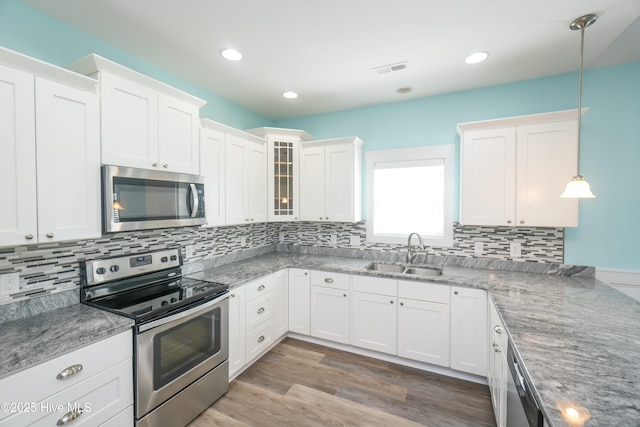 kitchen featuring a sink, glass insert cabinets, tasteful backsplash, appliances with stainless steel finishes, and white cabinetry