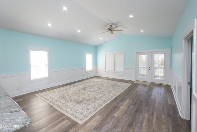 unfurnished living room featuring a wainscoted wall, french doors, dark wood finished floors, vaulted ceiling, and ceiling fan