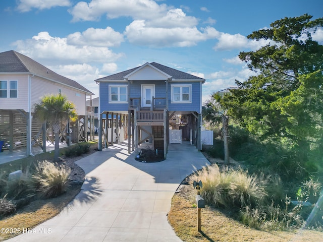 coastal inspired home with a carport, a shingled roof, driveway, and stairway