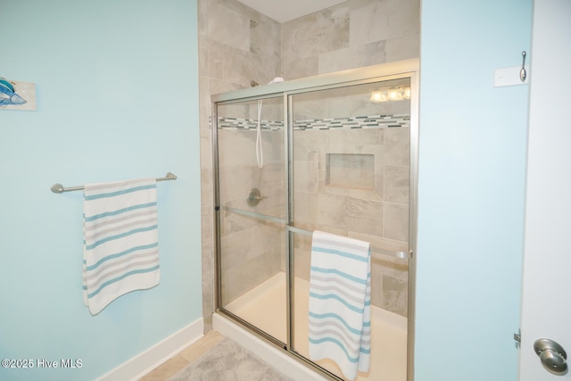 full bath featuring a shower stall and baseboards