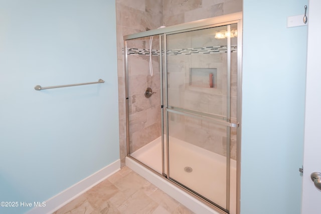 bathroom with a shower stall and baseboards
