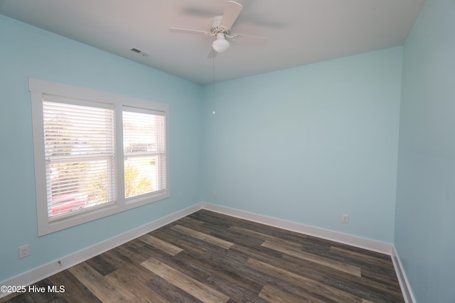 spare room featuring dark wood finished floors, visible vents, a ceiling fan, and baseboards