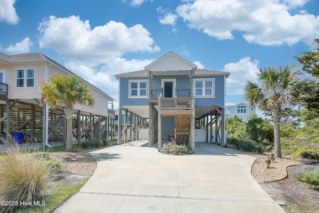 coastal home featuring a carport, driveway, covered porch, and stairs