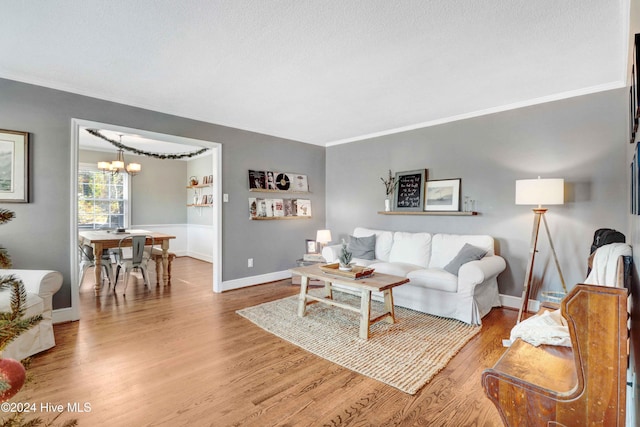 living room with crown molding, hardwood / wood-style floors, and an inviting chandelier