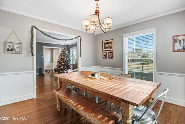 dining area with dark hardwood / wood-style floors, an inviting chandelier, and ornamental molding