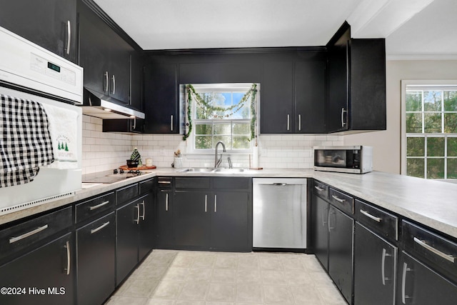 kitchen featuring black electric stovetop, tasteful backsplash, stainless steel dishwasher, white oven, and sink