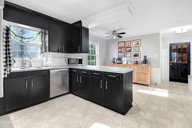 kitchen with kitchen peninsula, appliances with stainless steel finishes, ornamental molding, and sink