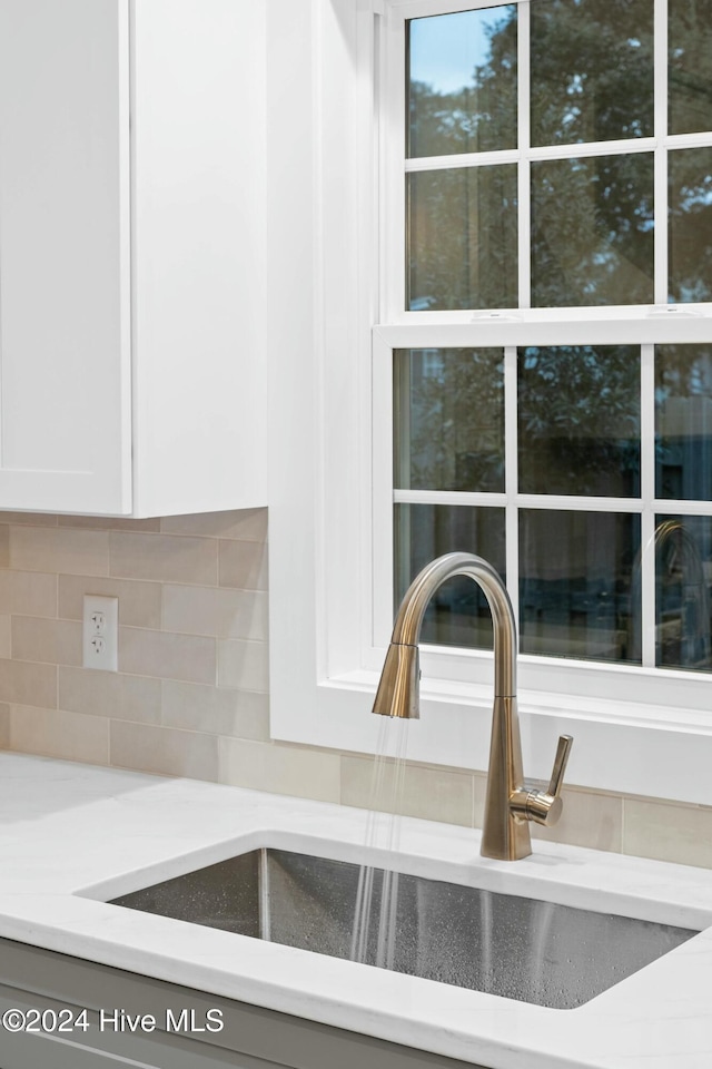 room details featuring white cabinets, backsplash, and sink