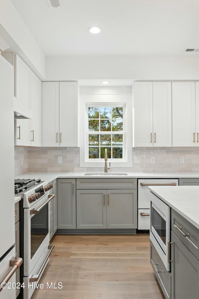 kitchen with ventilation hood, stainless steel appliances, sink, gray cabinets, and white cabinetry